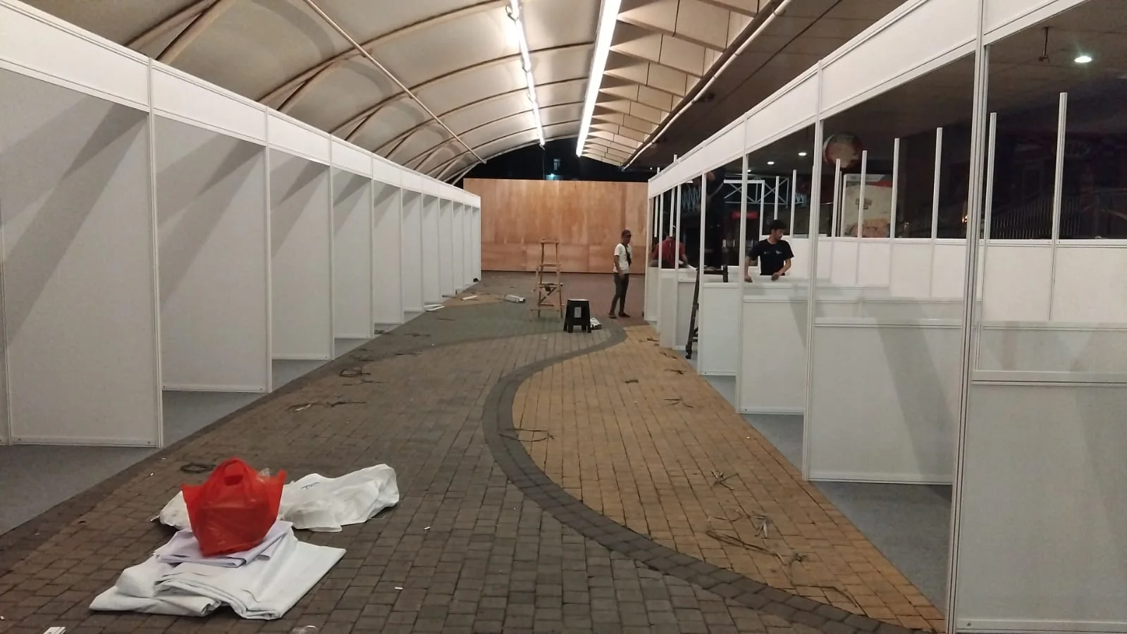 Pemasangan booth bazar modular di bawah tenda outdoor dengan partisi putih dan meja counter