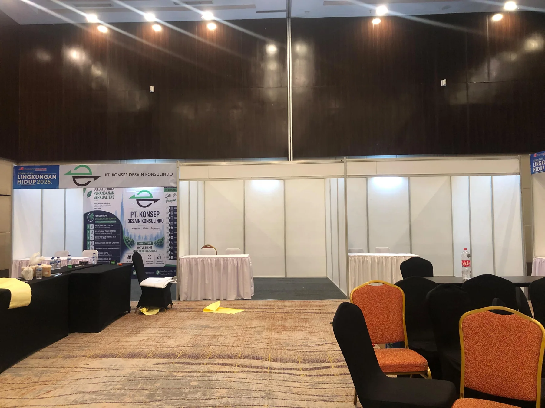Booth pameran untuk acara konferensi dengan fascia nama peserta, meja display dan pencahayaan area
