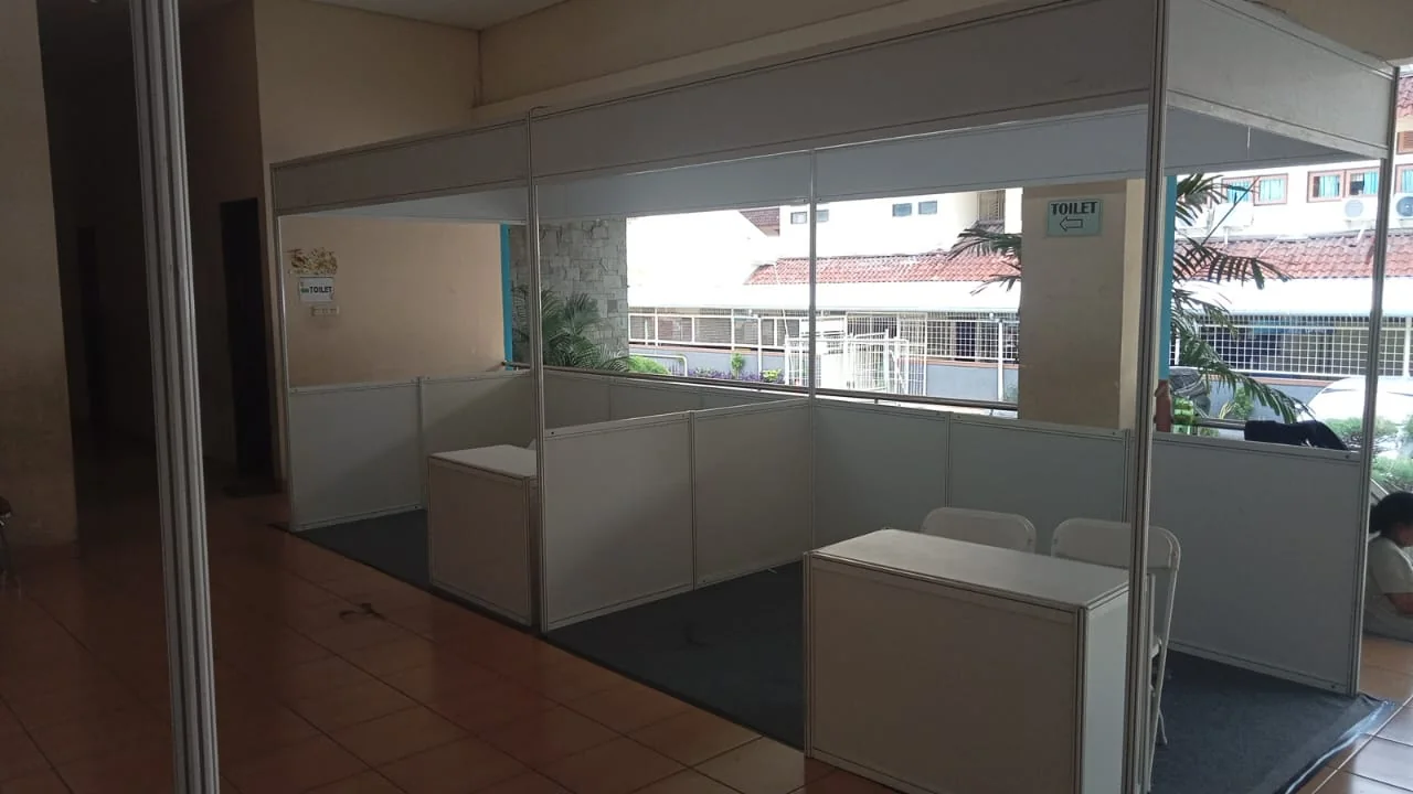 Booth pameran indoor sistem partisi putih lengkap dengan meja counter untuk registrasi atau display produk