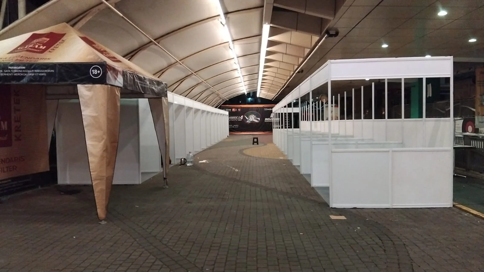 Koridor booth bazar di bawah tenda besar dengan deretan partisi modular dan area sirkulasi pengunjung