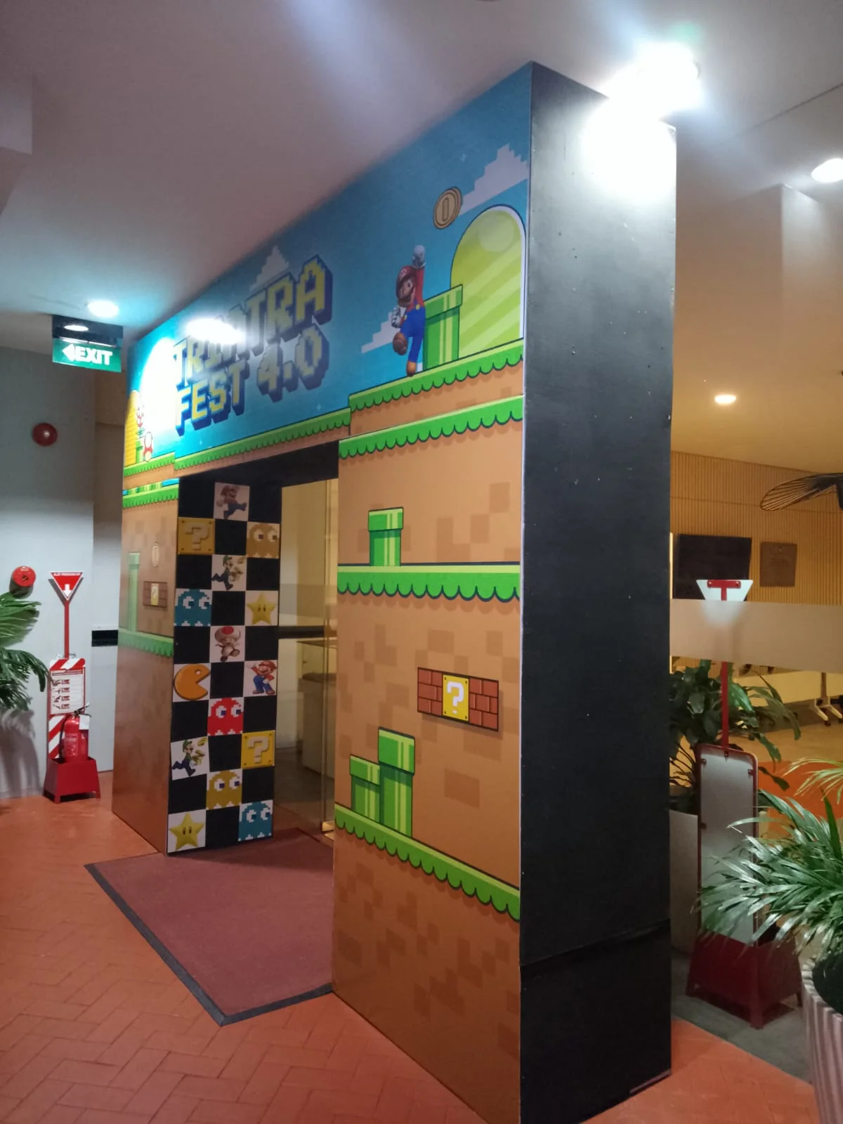 Entrance gate Triatra Fest 4.0 bertema retro game dengan grafis pixel art, balok warna-warni dan pencahayaan area