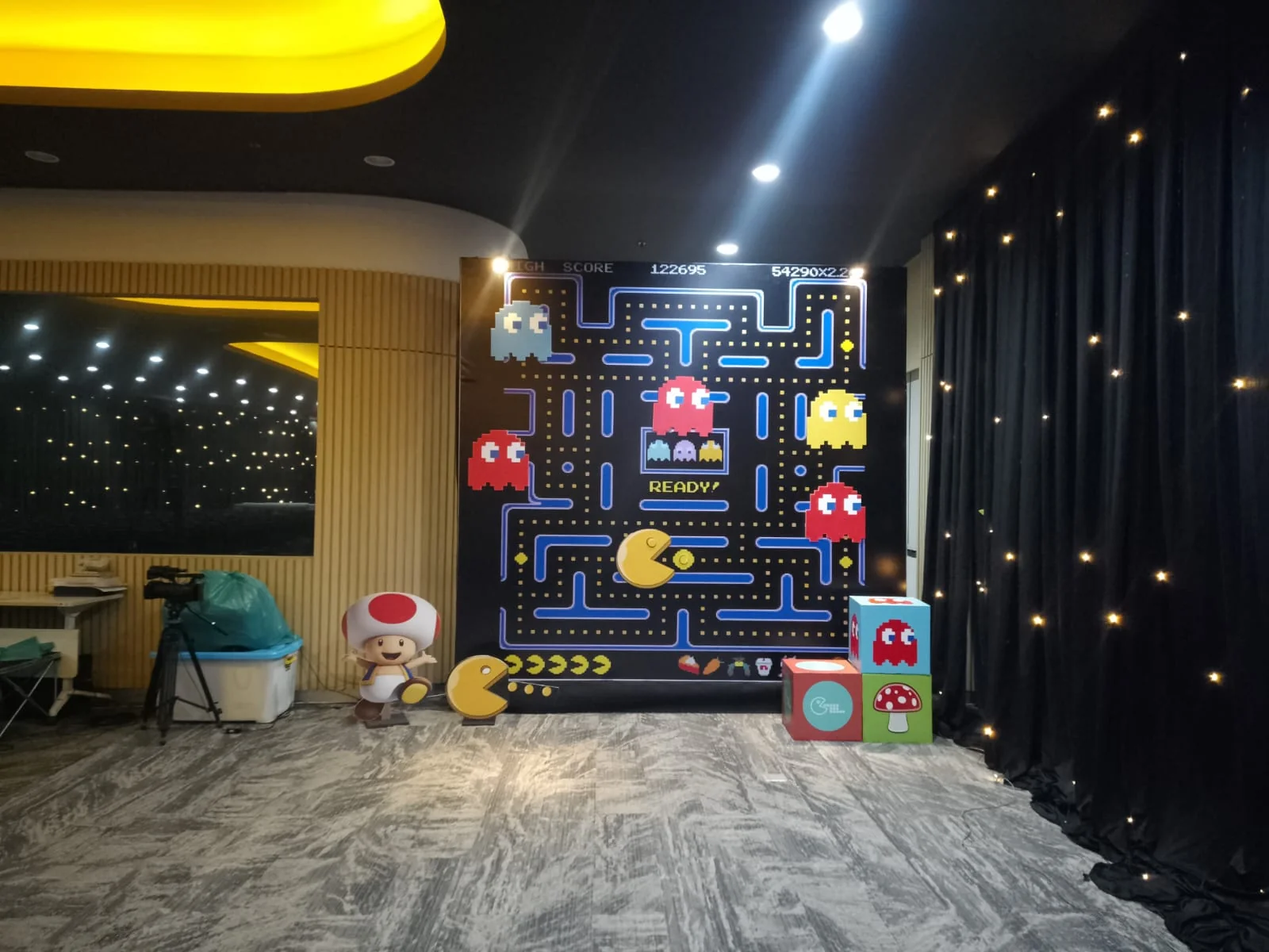 Photo corner Triatra Fest bertema Pac-Man dengan maze pixel art, karakter gim dan lampu dekoratif