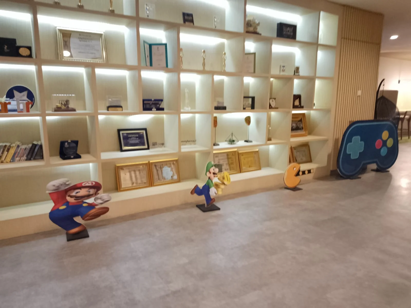 Area product display Triatra Fest dengan rak berlampu, dekorasi karakter Mario dan properti kontrol gim