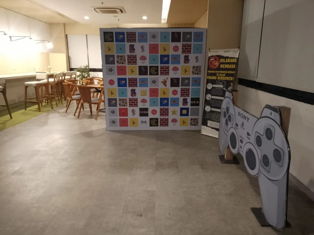 Sponsor photowall Triatra Fest lengkap dengan properti kontrol PlayStation berukuran besar untuk sesi foto