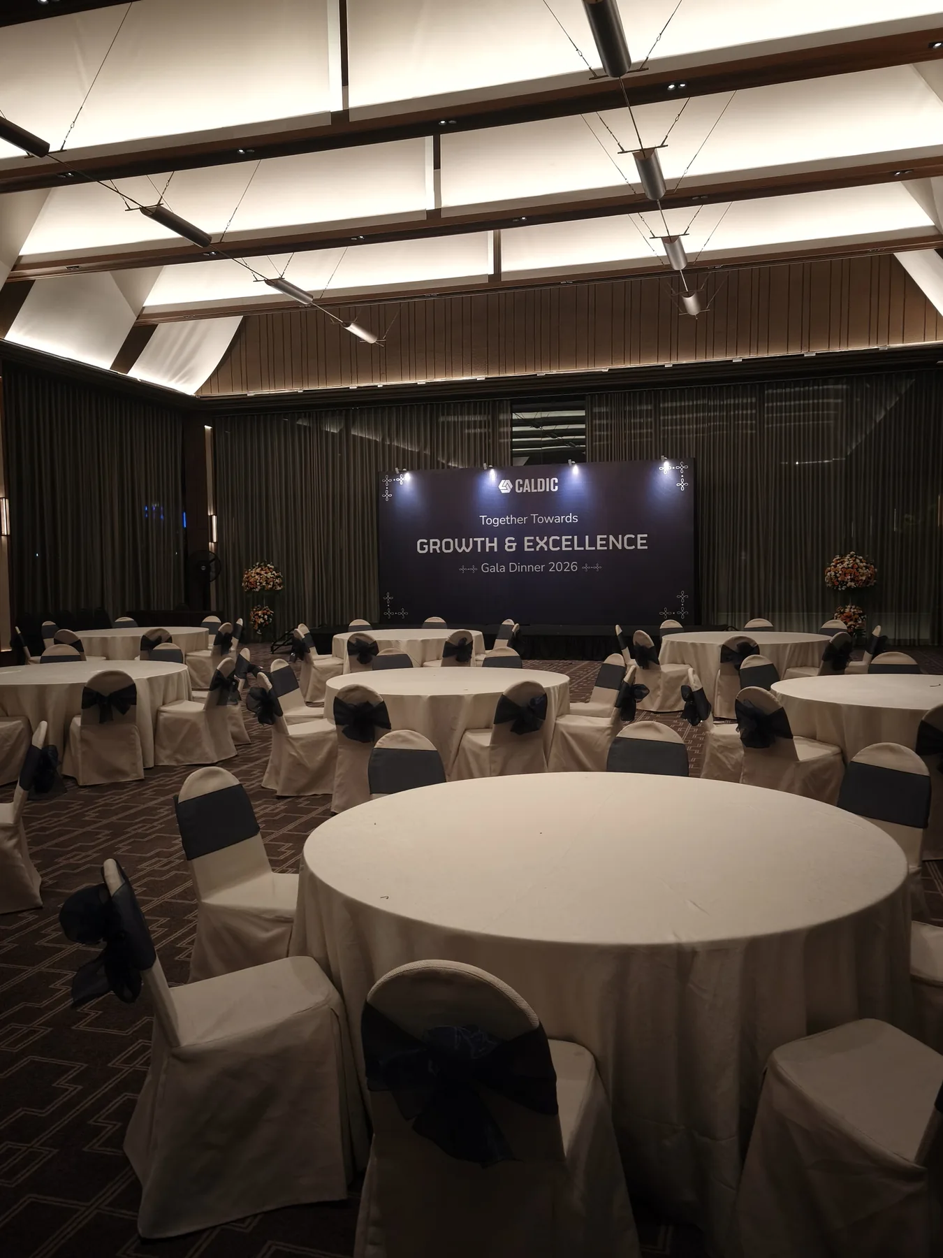 Meja bundar dan panggung Caldic dalam ruang gala dinner