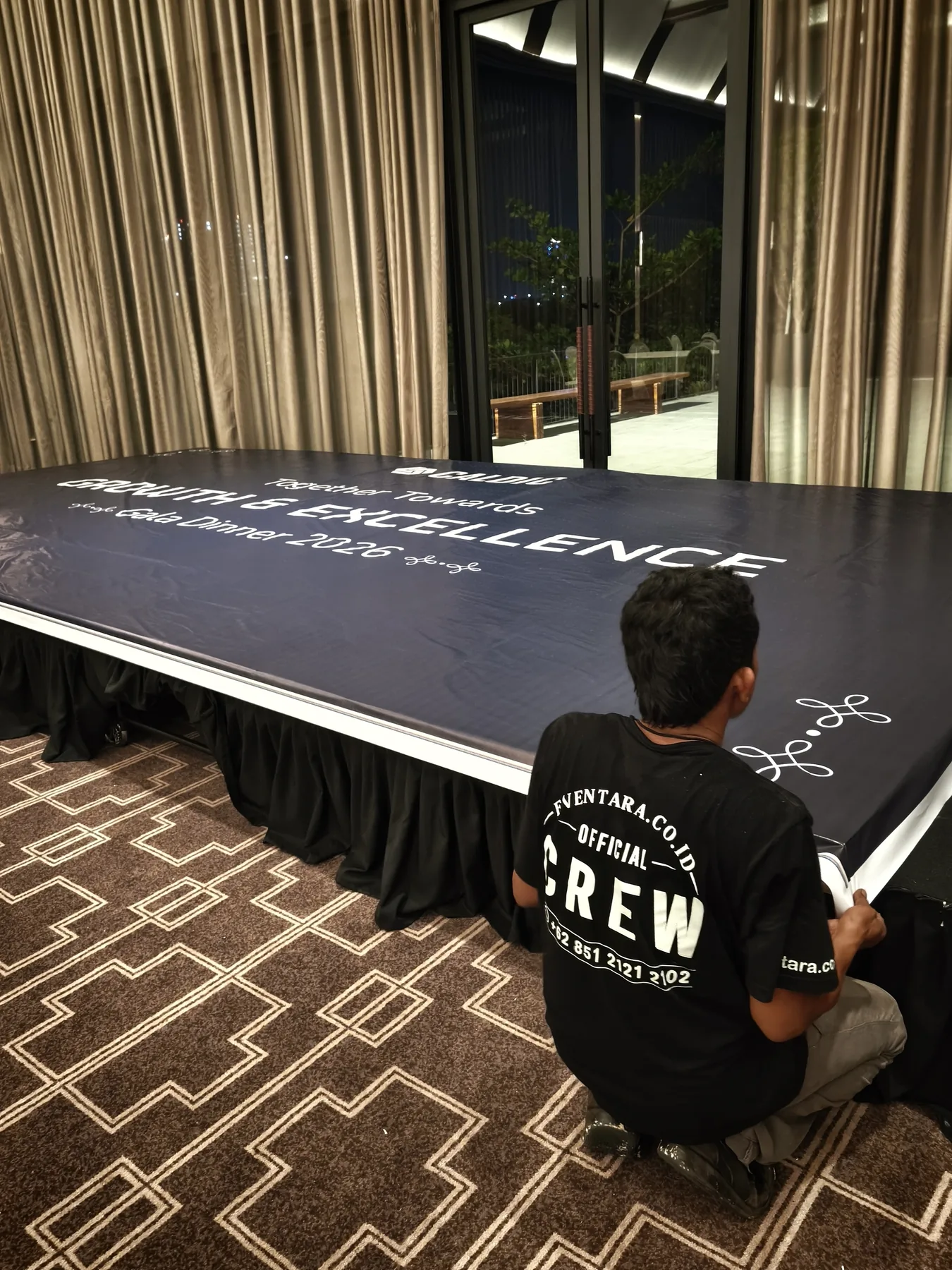 Kru Eventara  menyiapkan meja dan panggung bertema Growth & Excellence