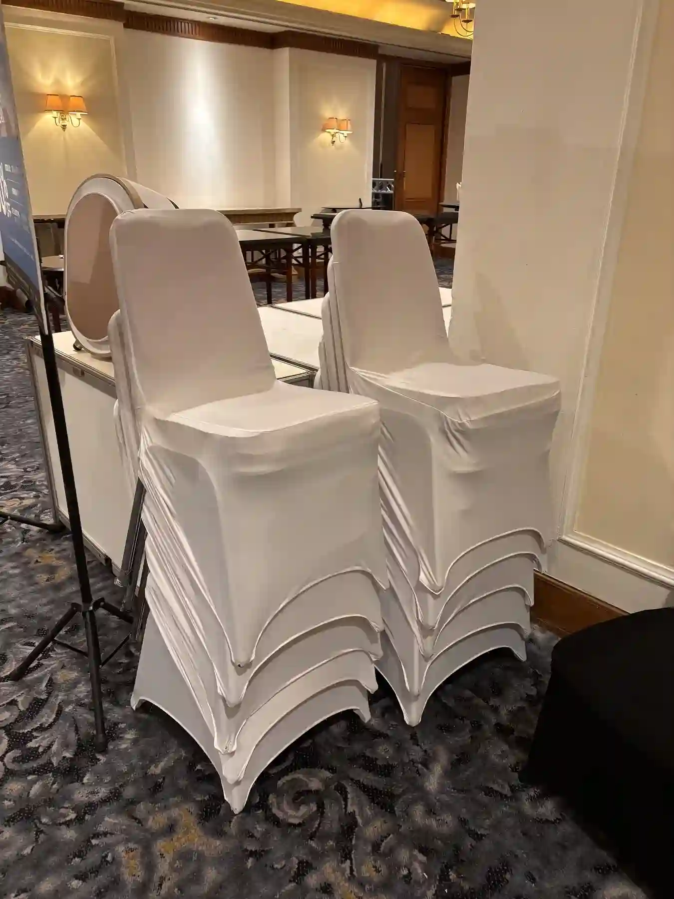 Kursi dengan cover putih yang ditumpuk untuk persiapan event ballroom
