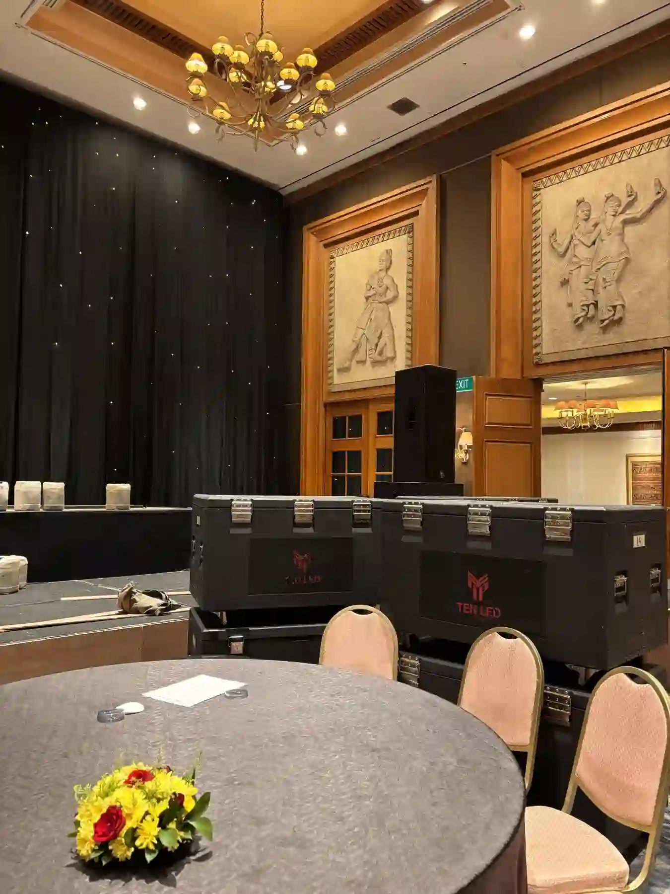 Meja bundar dengan centerpiece bunga di area acara ballroom