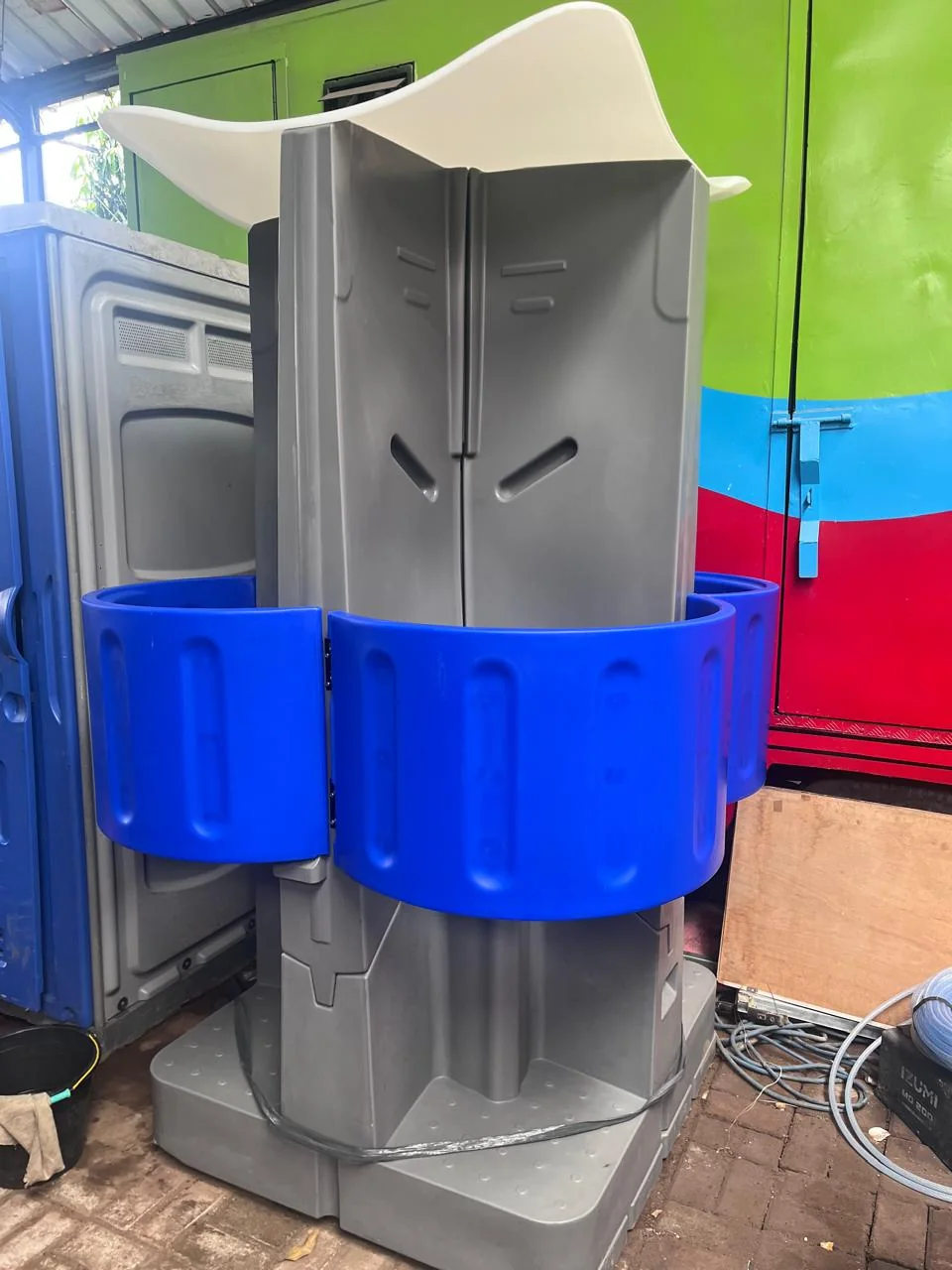 Detail urinoir portable pria dengan sekat privasi biru, difoto di area penyimpanan
