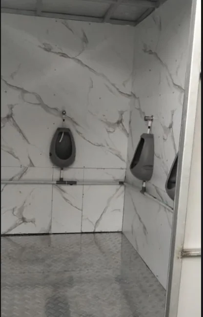 Tiga urinoir dinding pria di ruang sanitasi berpanel marmer